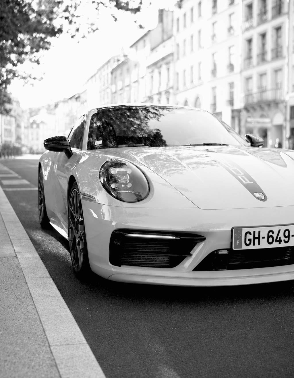 Porsche blanche dans une avenue bordée d'immeubles