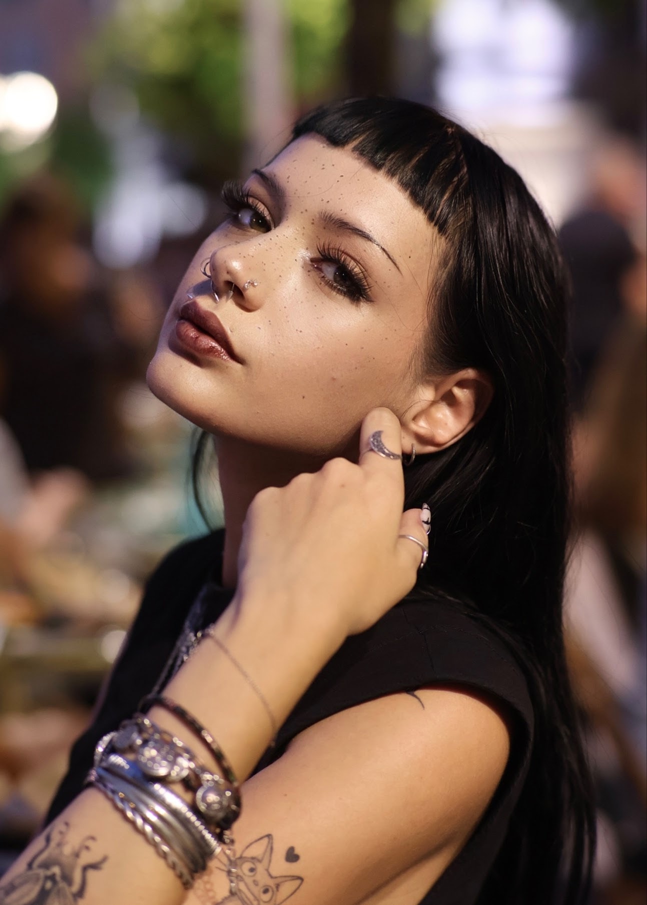 Portrait de nuit d'une jeune femme à frange, bracelets et tatouages