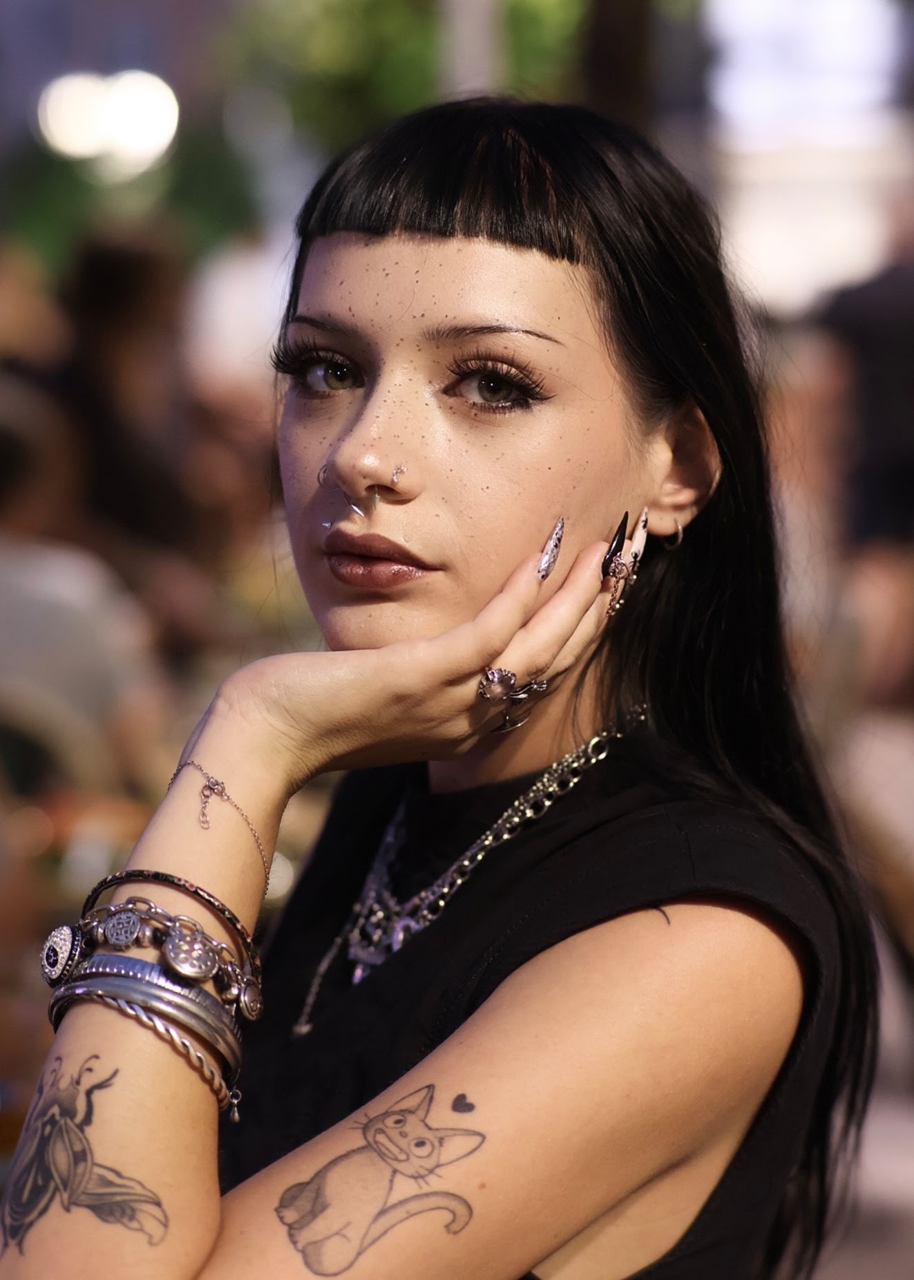 Portrait de nuit d'une jeune femme à frange, main contre la joue